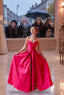A girl twirls in a pink satin prom ballgown at Proms & Beyond while four rain-soaked classmates press their noses against the shop window in envy.