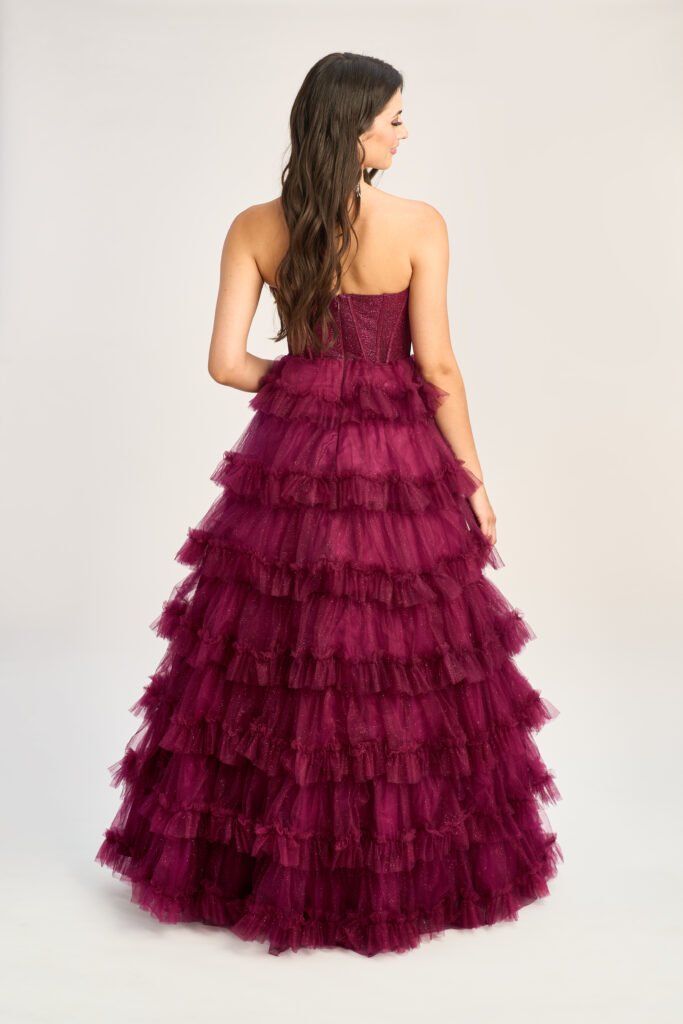 Model wears a beautiful pink prom gown with an open back, which contrasts perfectly with peach prom dresses for a romantic appearance.